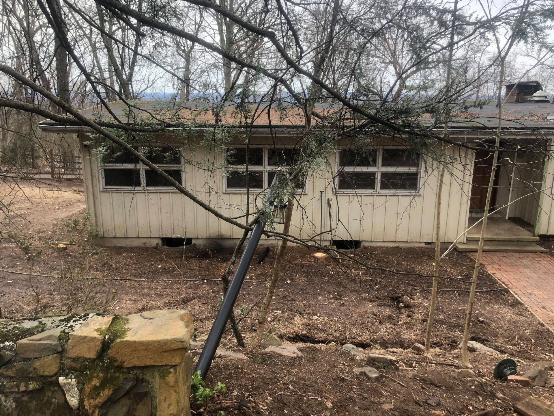 A white house is sitting in the middle of a dirt field surrounded by trees.