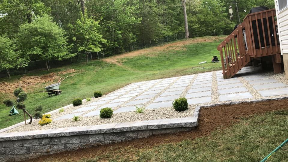 A patio with a wooden deck in the backyard of a house.