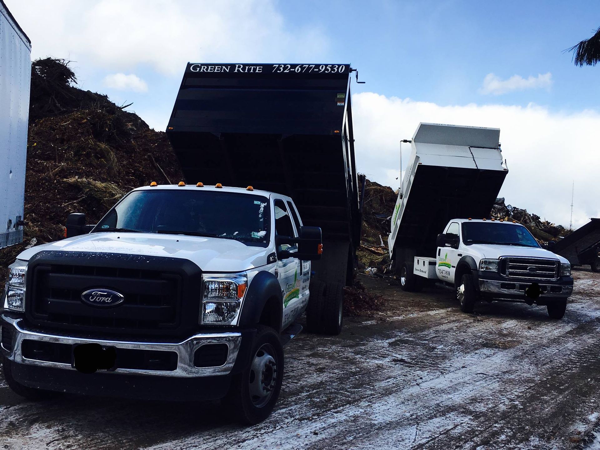 Two dump trucks are parked next to each other on a snowy road