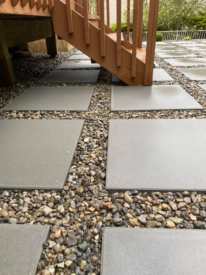 A wooden staircase is surrounded by gravel and tiles