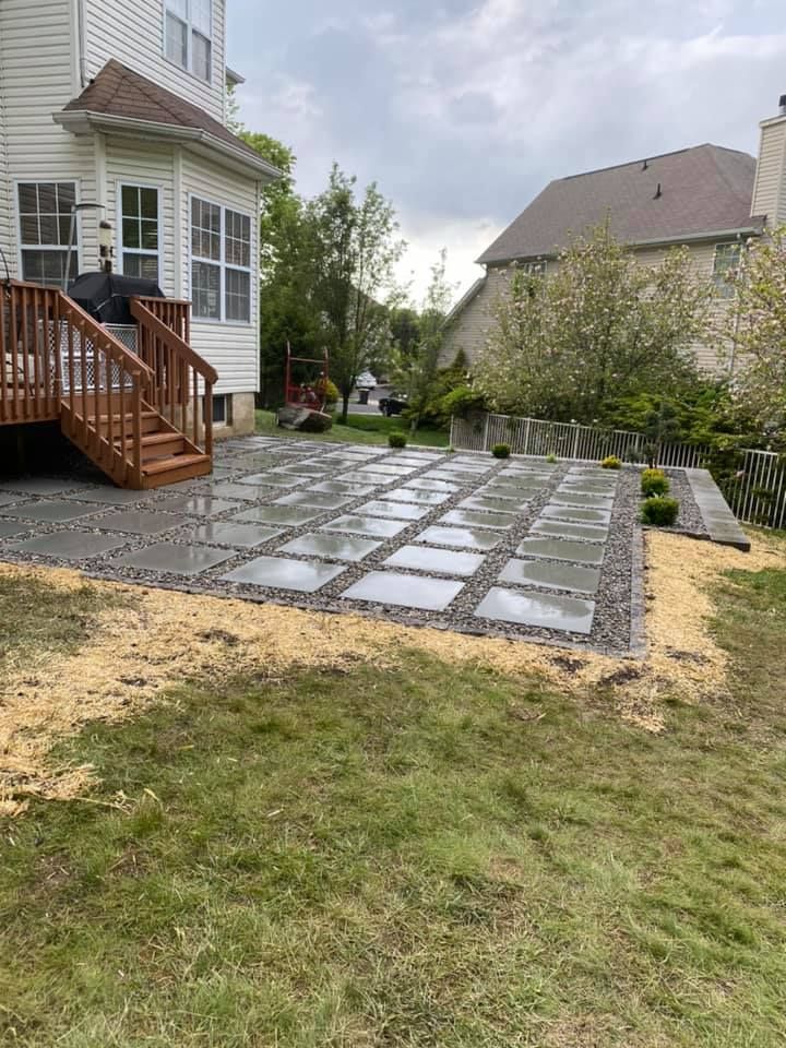 A patio with a deck and stairs in the backyard of a house.