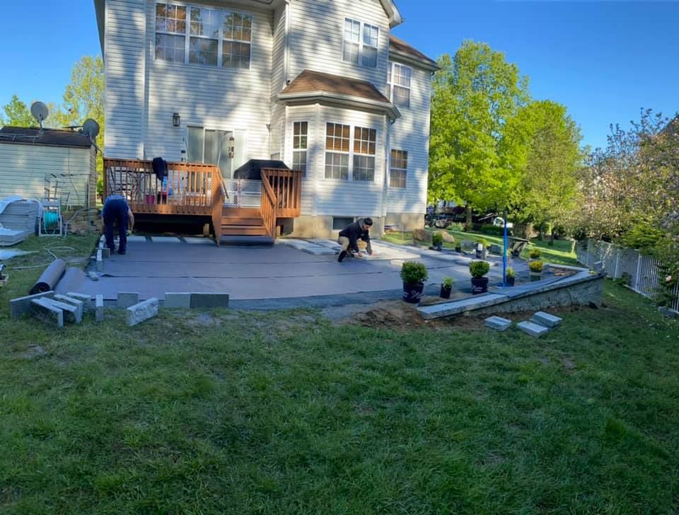 A man is working on a patio in front of a house