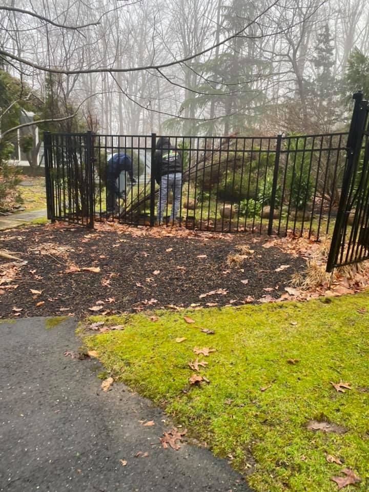 A couple of people are working on a fence in a yard.