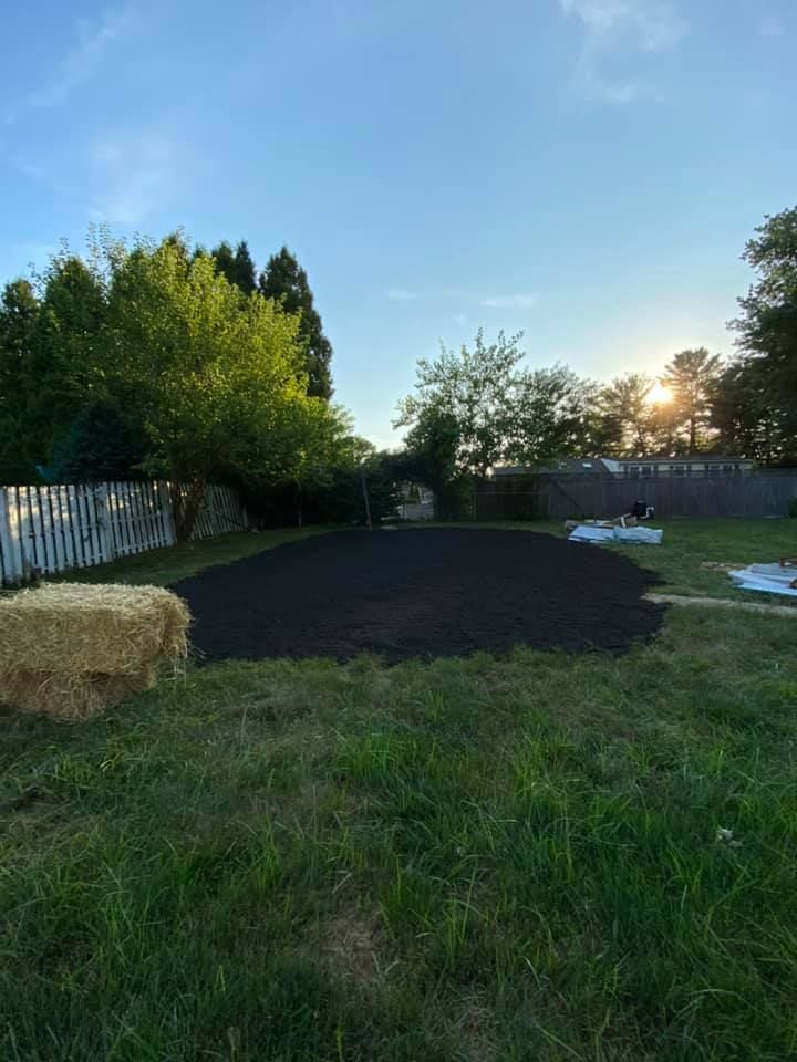 A backyard with hay bales and a fence in the background.
