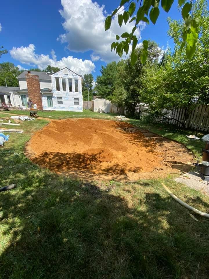 A large pile of dirt is in the backyard of a house