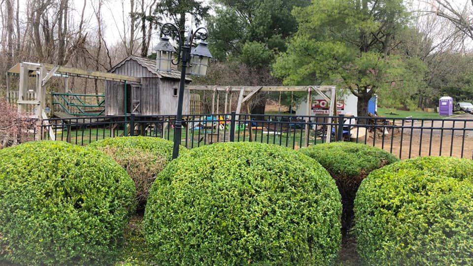 A fence with a bunch of bushes in front of a house.