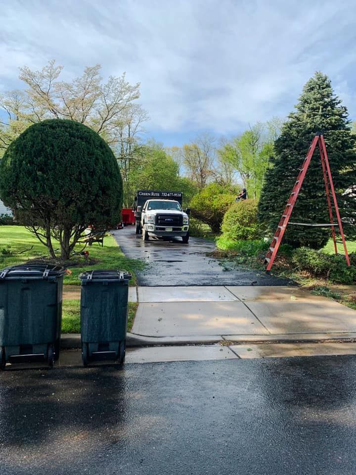 A white truck is parked in a driveway next to a ladder.