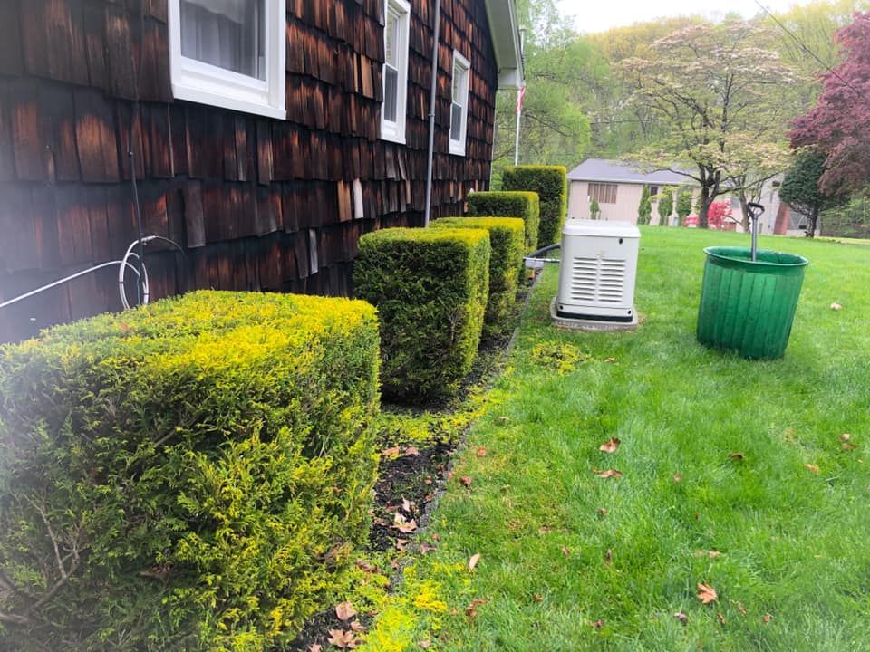 A house with a generator and a green trash can in front of it