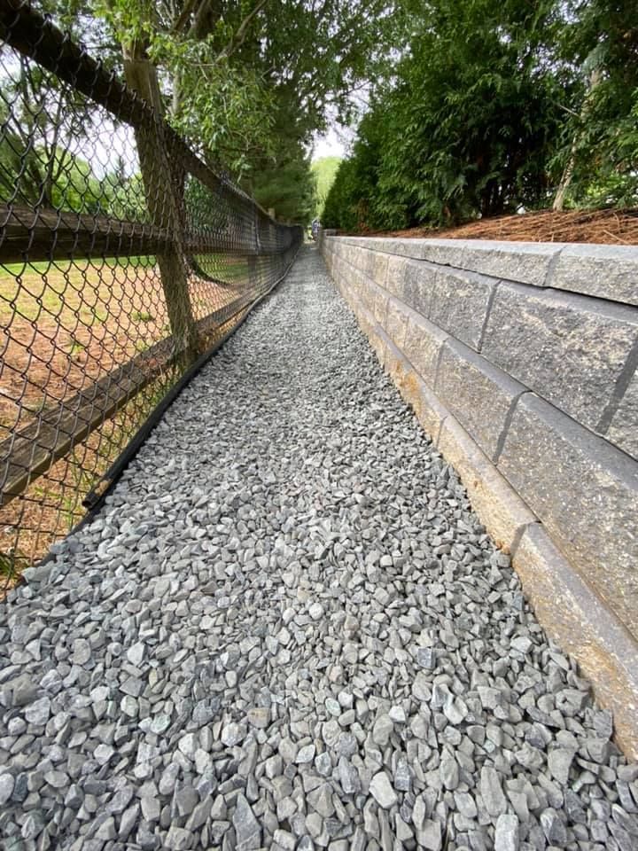 A gravel path leading to a fence and a baseball field