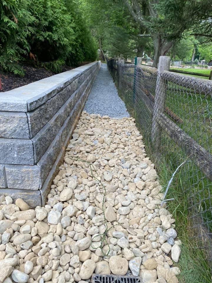 A stone walkway leading to a wooden fence surrounded by rocks