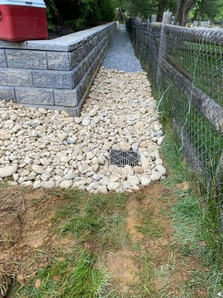 A stone walkway leading to a fence with a red cooler 