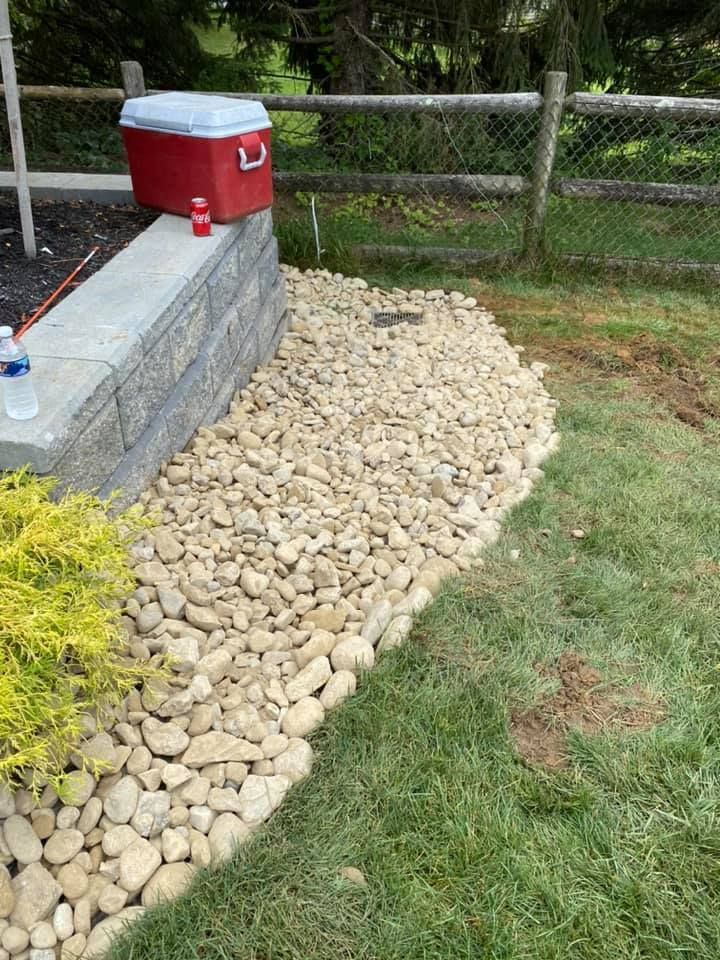A red cooler is sitting on top of a stone wall next to a fence.