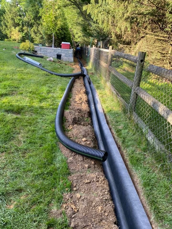 A hose is laying in the dirt next to a wooden fence