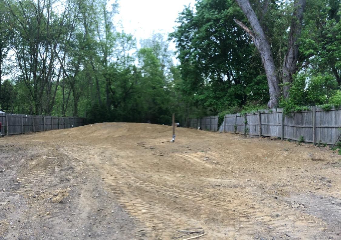 A dirt road with a wooden fence in the background