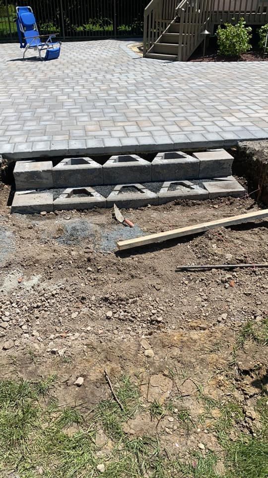 A patio is being built in a backyard with a blue chair in the background