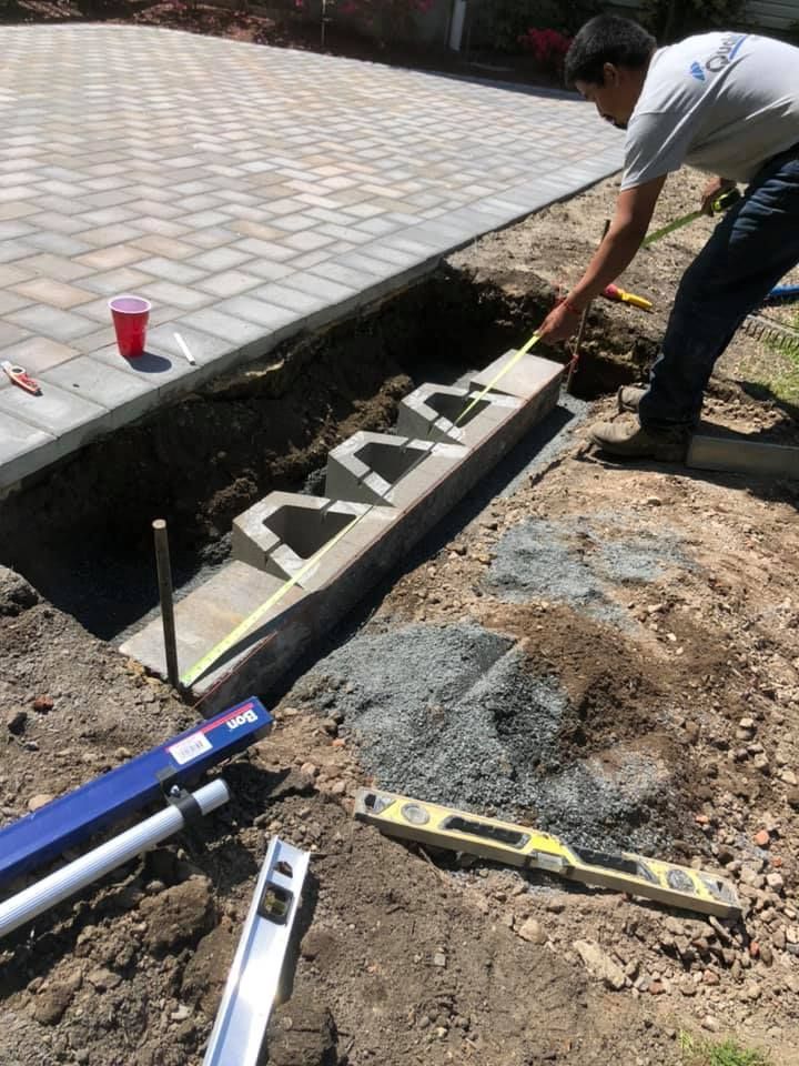 A man is measuring a concrete curb with a tape measure
