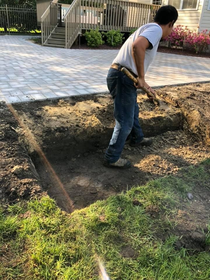 A man is digging in the dirt with a shovel.