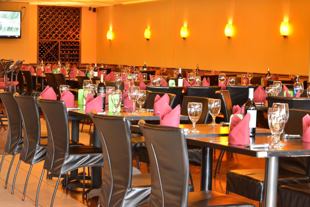 Dimly lit restaurant dining room with set tables, red napkins, wine glasses, and wall art