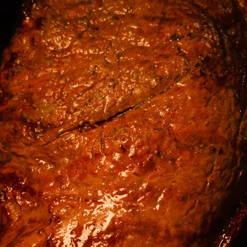 Close-up of a shiny brown cooked meat surface with a diagonal crack.