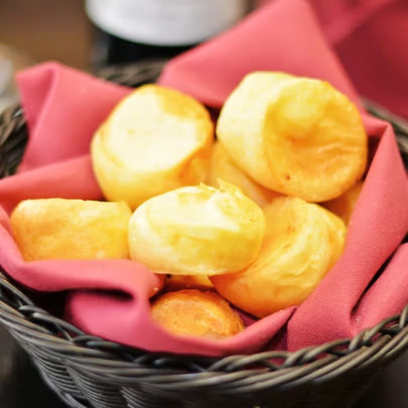 Basket of golden fried bread rolls on a pink napkin