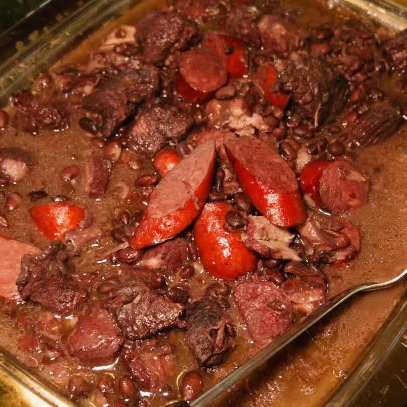 Baked berry cobbler in a glass dish, with dark fruit filling and sliced strawberries on top