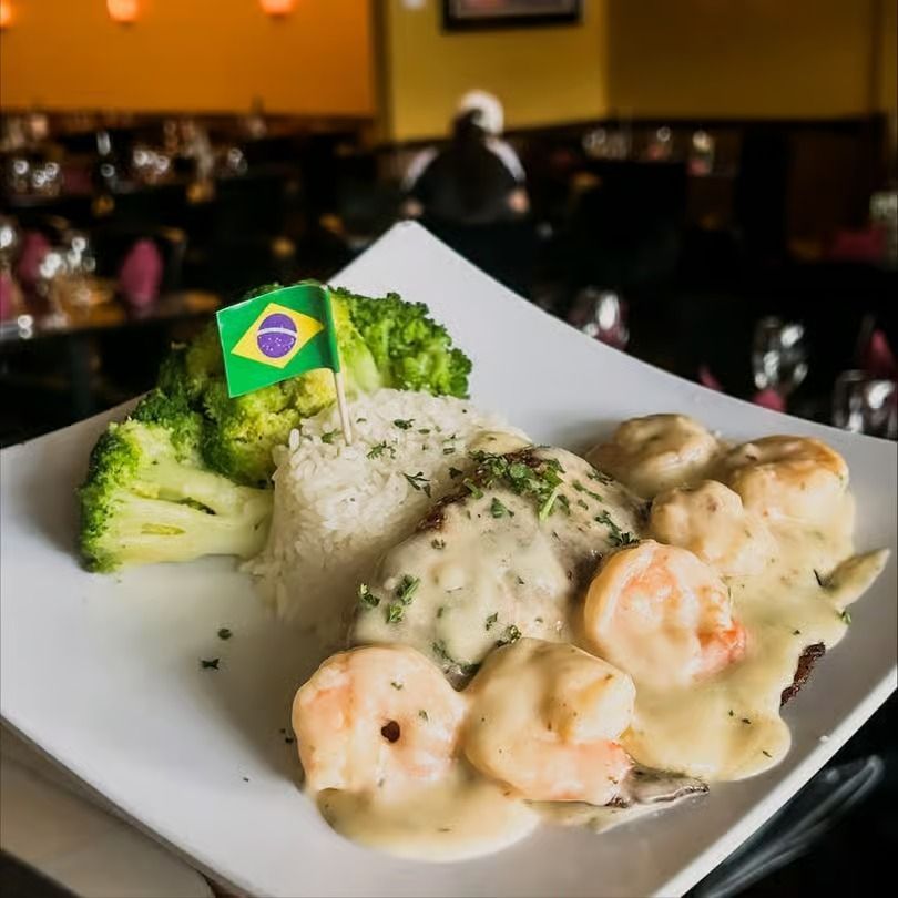 Shrimp in creamy sauce with rice and broccoli on a white plate in a restaurant setting