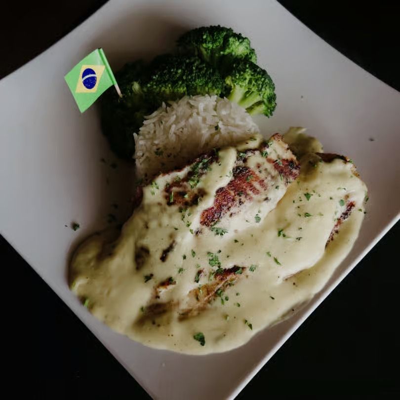 Brazilian flag toothpick in a plated rice meal with broccoli and creamy sauce