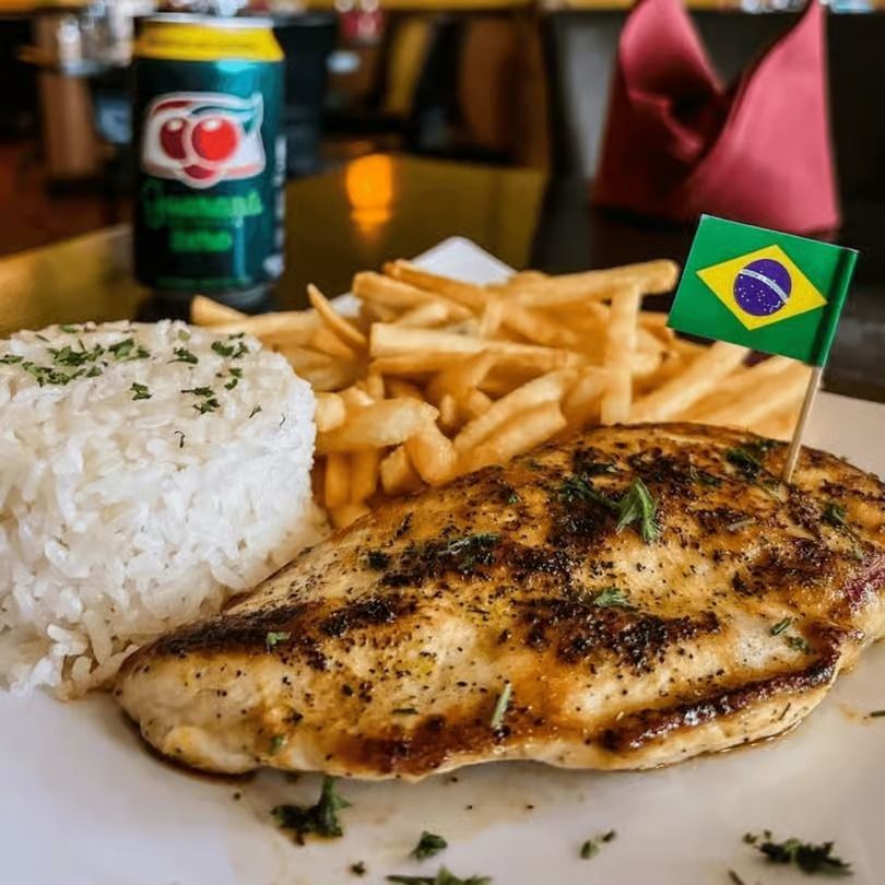 Grilled chicken with rice and fries on a plate, garnished with a small Brazilian flag.