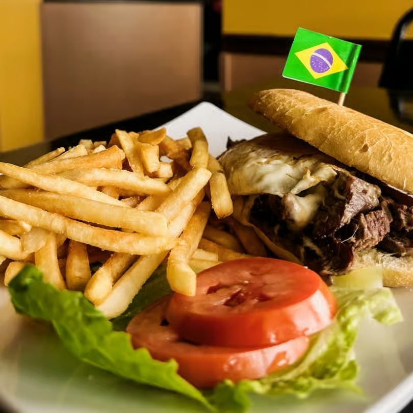Burger, fries, and tomato slices on a plate with a small Brazilian flag toothpick.