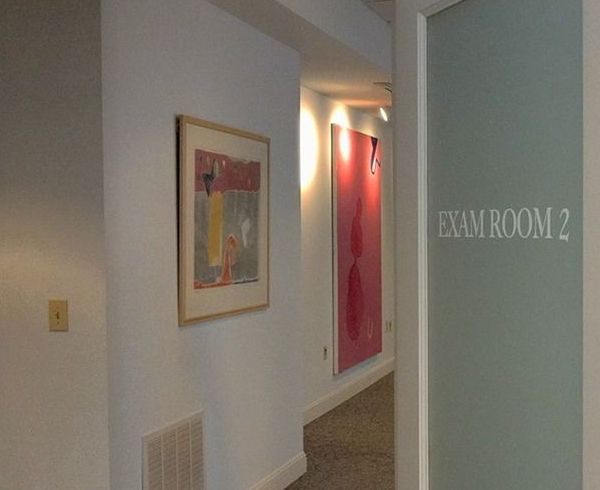 A hallway with a glass door that says exam room 2