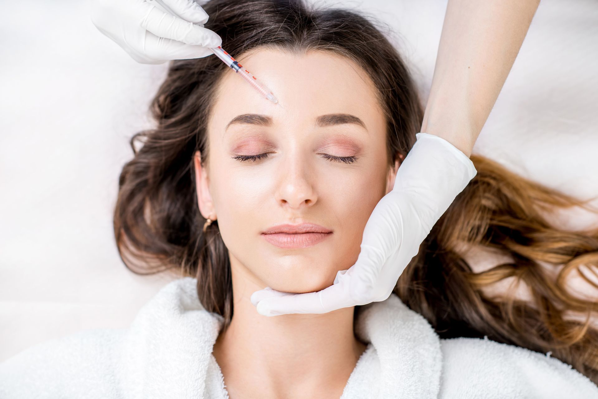 A woman is getting an injection in her forehead.