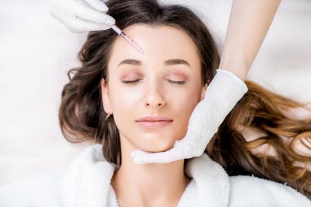 A woman is getting an injection in her forehead.