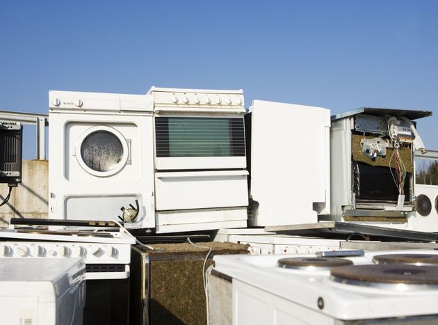 Abandoned rooftop with discarded appliances and metal debris under a clear blue sky