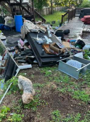 Backyard deck cluttered with debris, broken furniture, and bins after storm damage