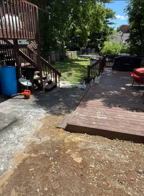 Backyard deck and concrete patio beside stairs, with a grassy yard in the background.