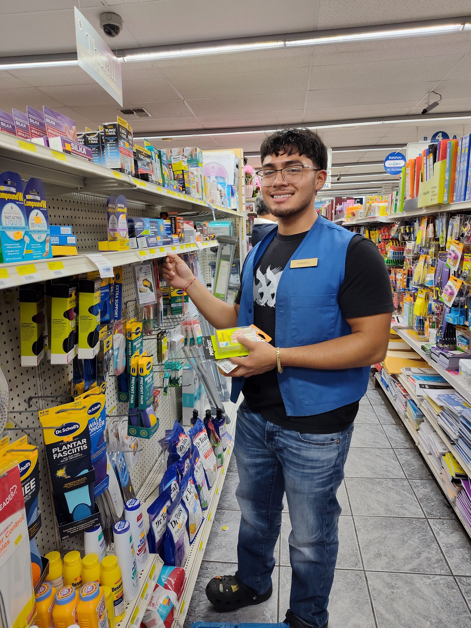 A man in a blue vest is standing in a grocery store.