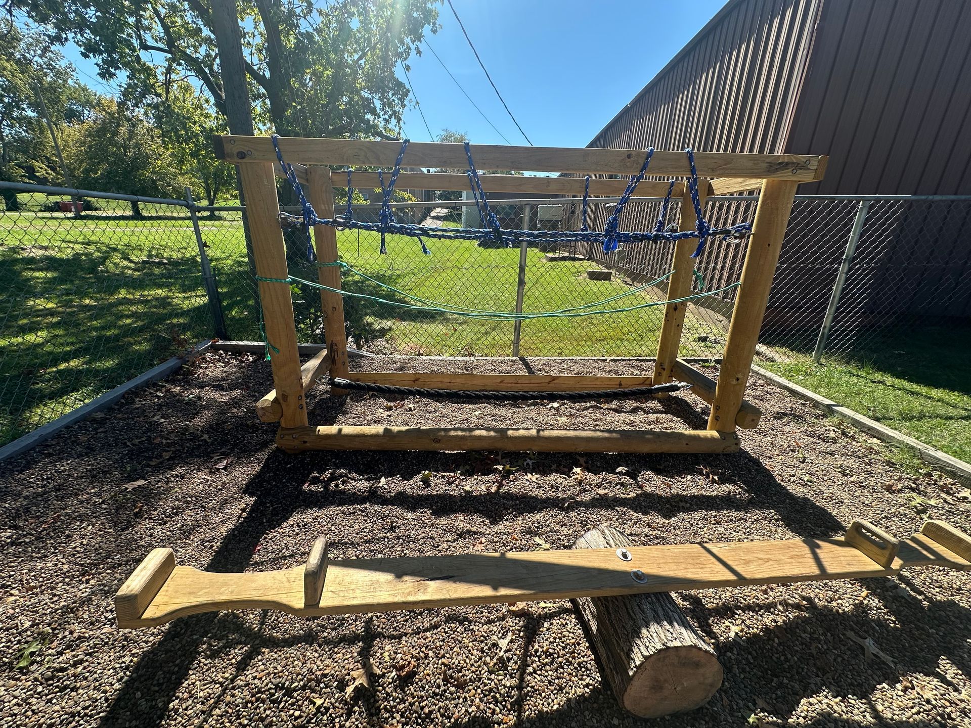 A wooden swing set is sitting on top of a pile of mulch in a park.