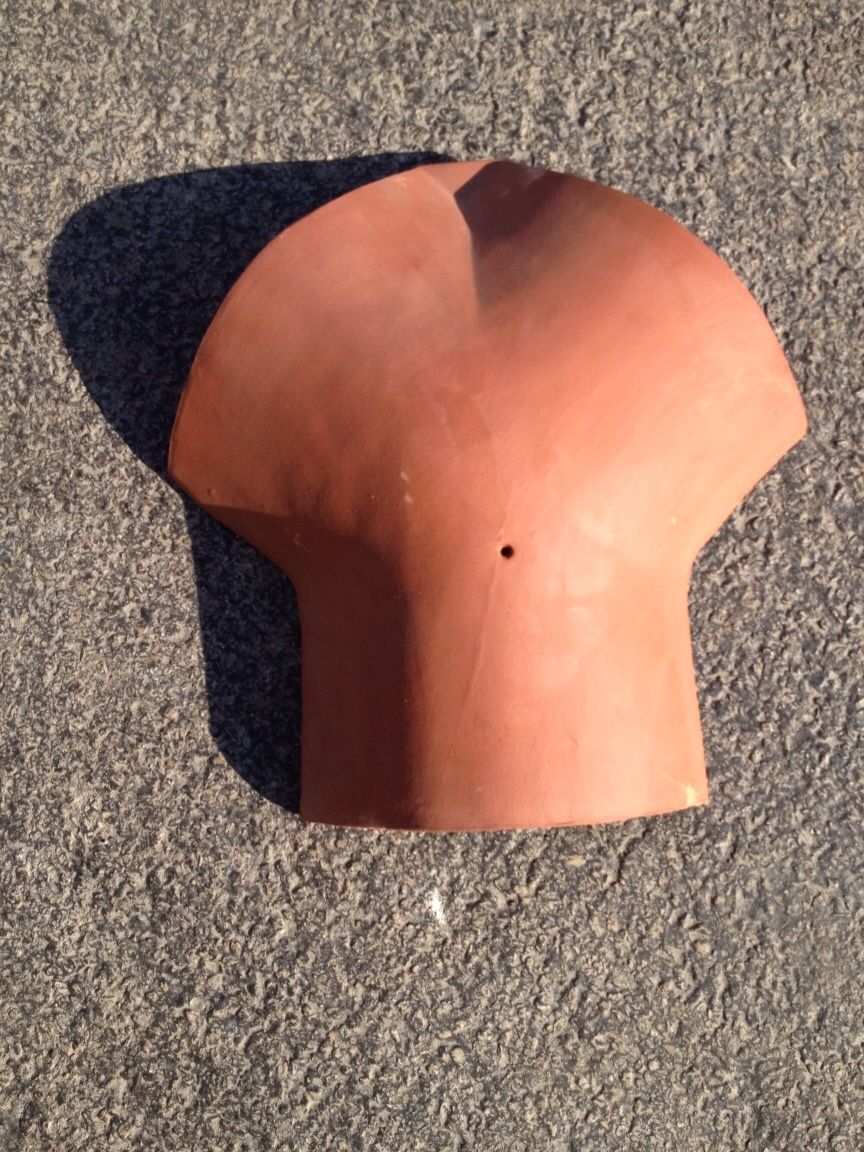 A brown custom roof tile with a hole in the middle is sitting on the ground