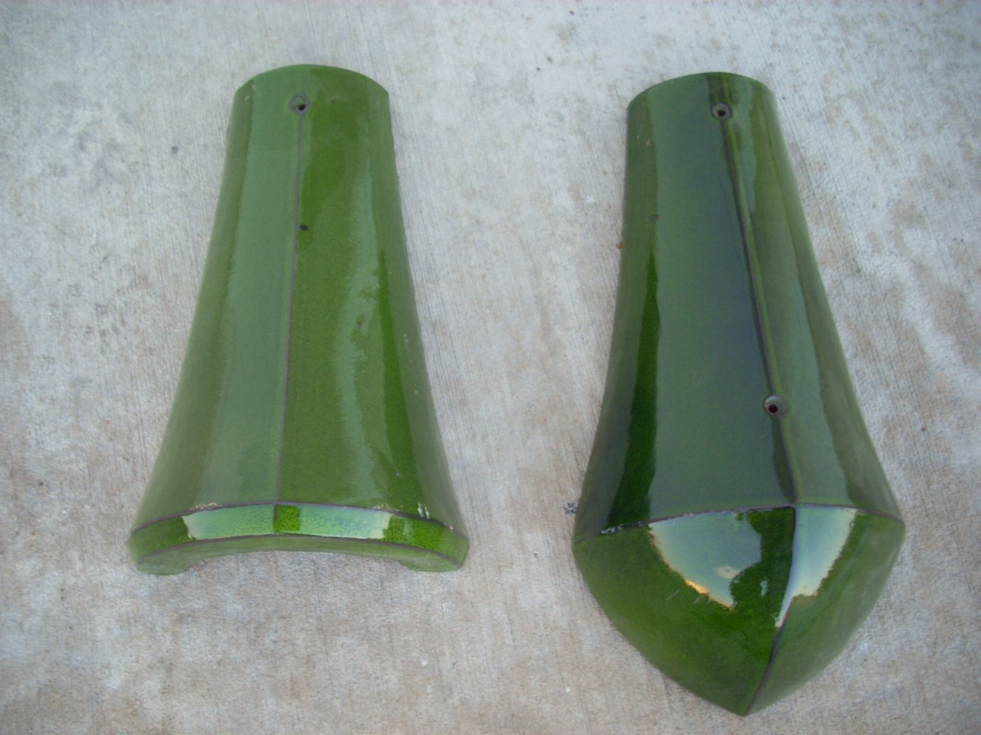 Two green custom roof tile are sitting on a white surface