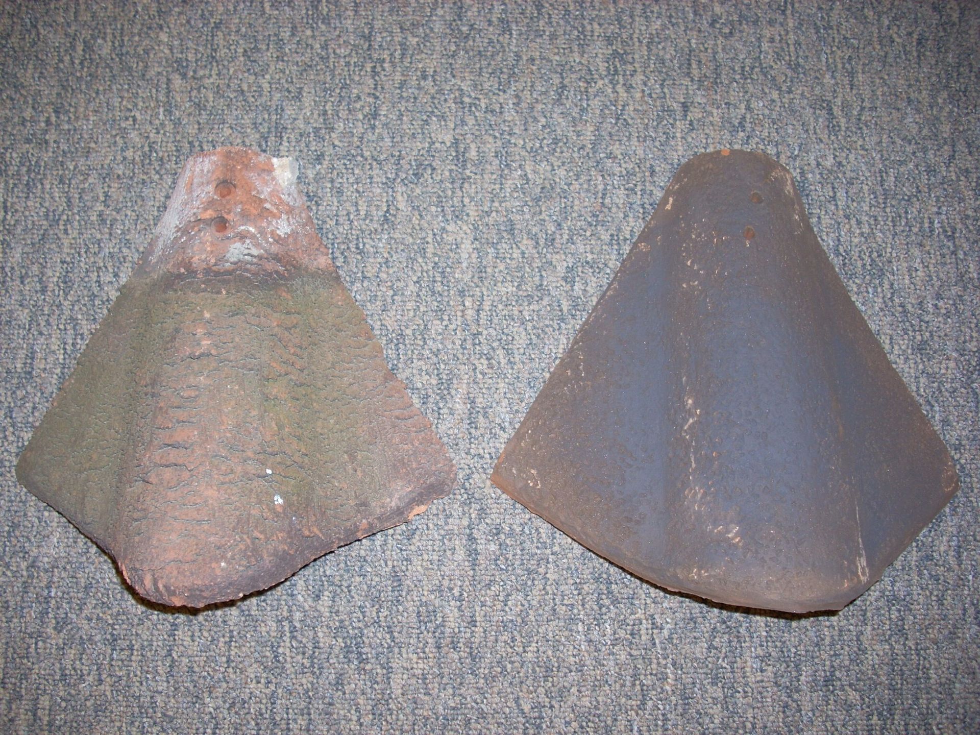 Two pieces of custom roof tile are sitting on a gray surface
