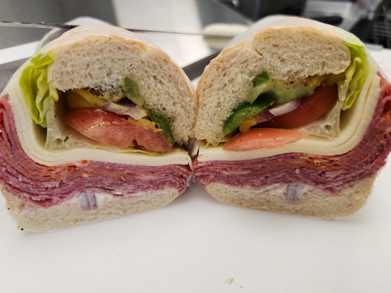 A sliced sandwich with layers of meat, cheese, lettuce, tomato, and vegetables.