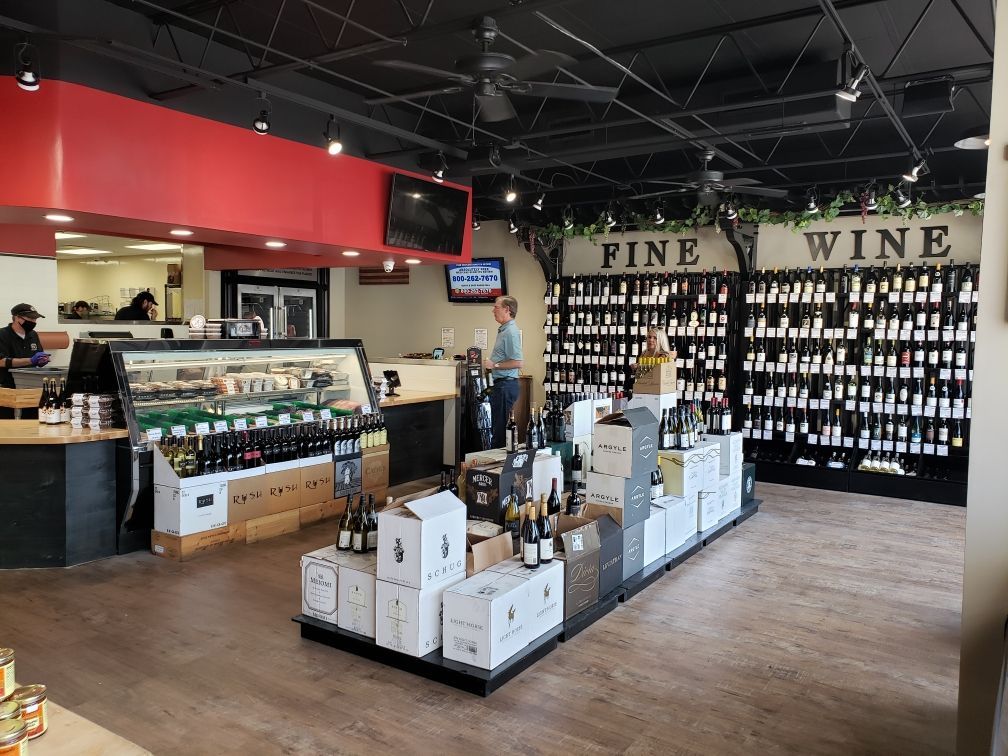 Wine shop interior with wine displays, a checkout counter, and a customer.