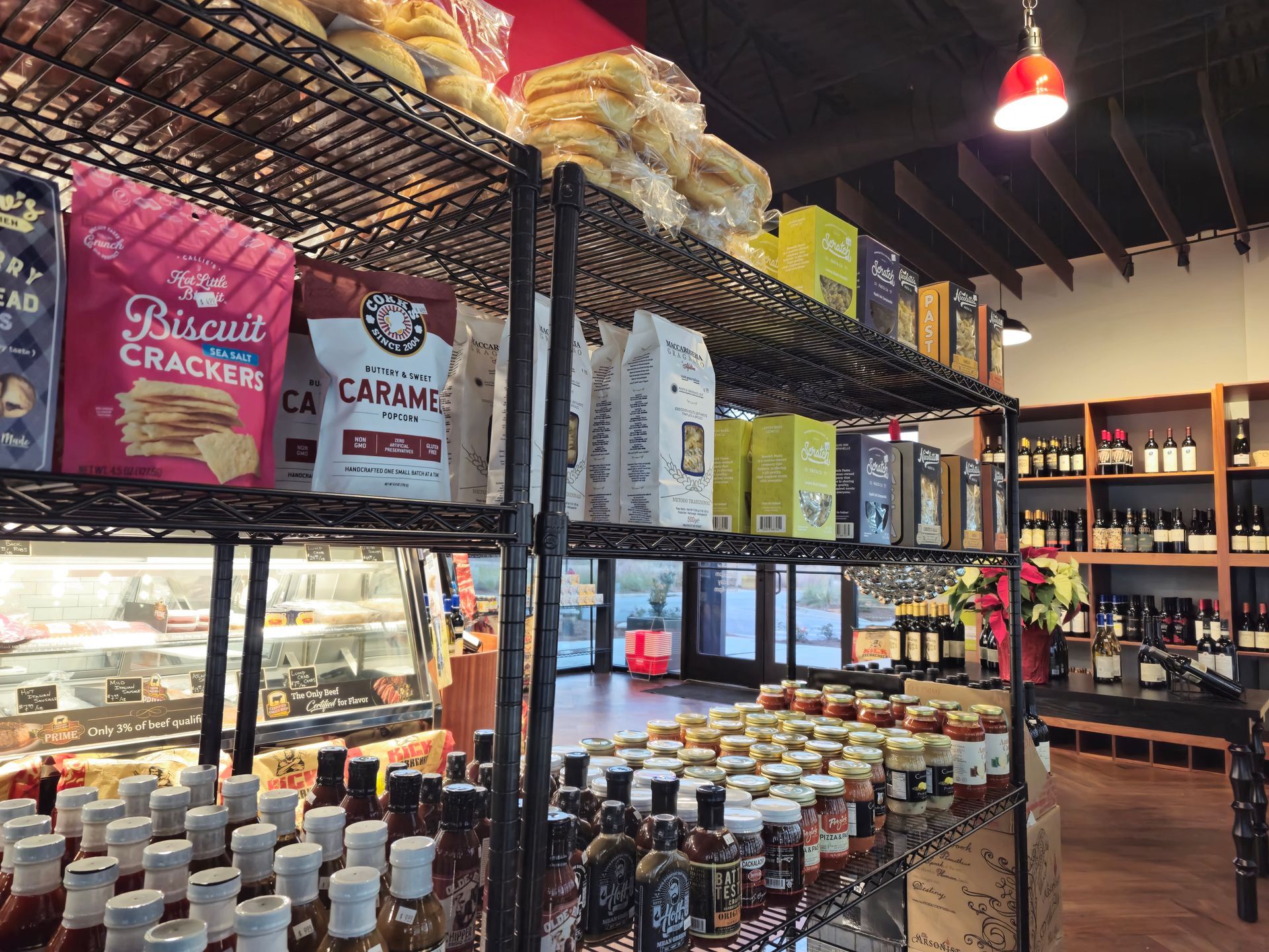 Shelves stocked with crackers, sauces, and jars. Wine bottles on a wooden rack. Store interior.