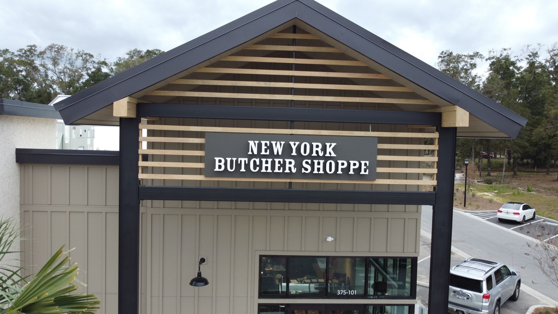 New York Butcher Shoppe storefront with sign. Gray, black, and tan building.