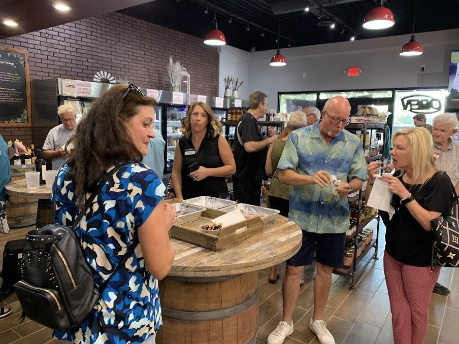 People at a store, some looking at items. Interior shot with a wooden table and red lighting.