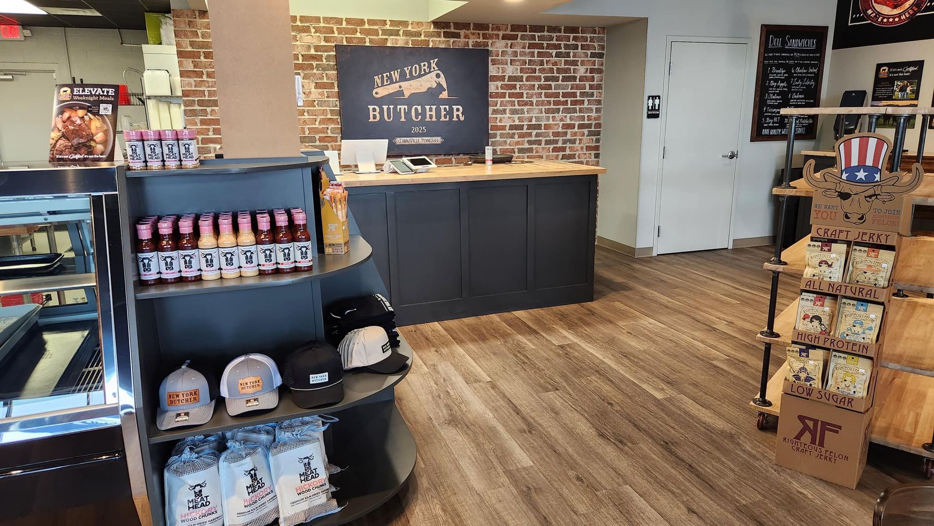 Interior of a store with merchandise displays and a counter, brick wall, and wooden floors.
