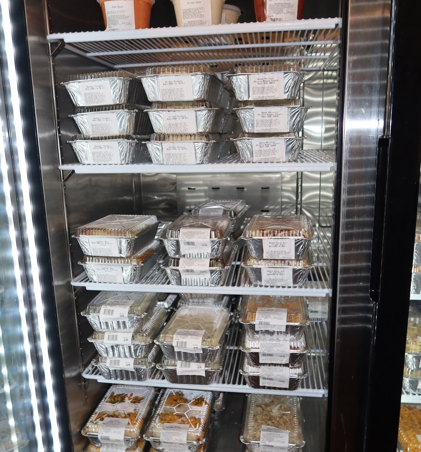 Refrigerator display with prepared food in foil containers.