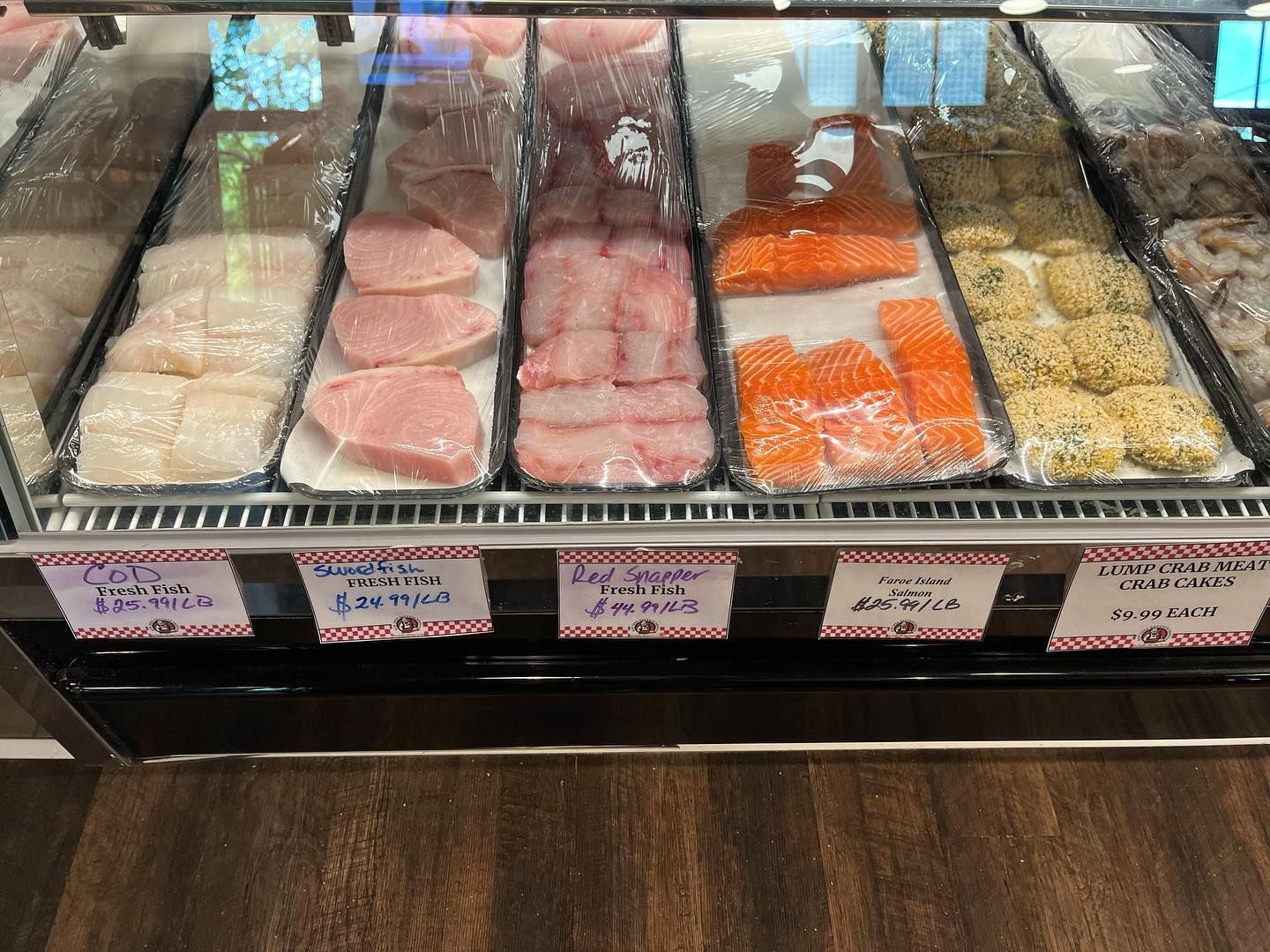 Display case of fresh seafood with labeled packages; fish, salmon, and prepared items.