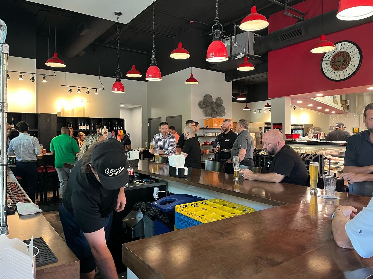 Interior of a busy restaurant with a bar, patrons, red and black decor.