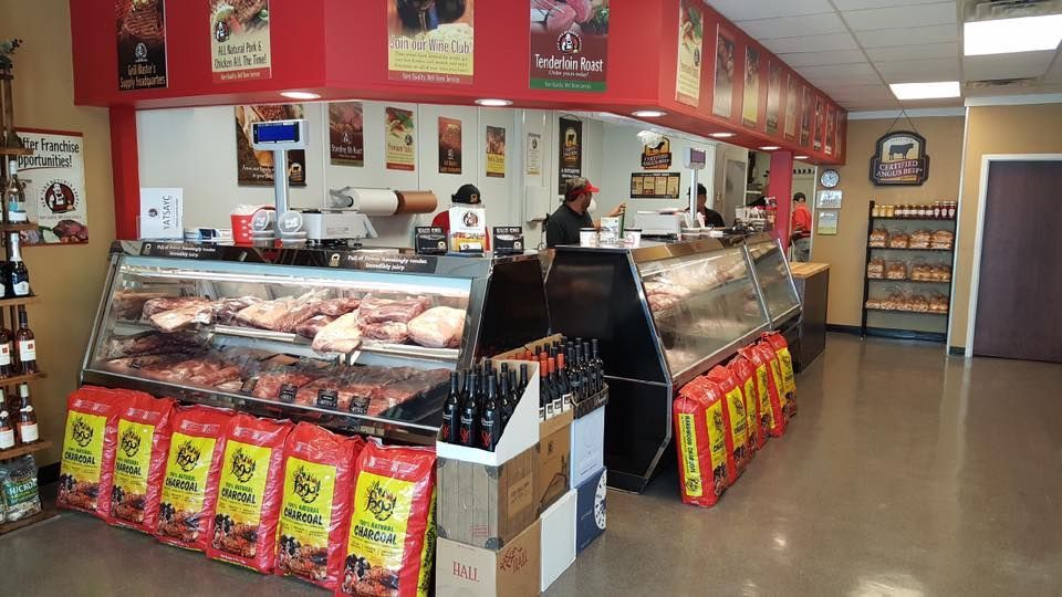 Butcher shop interior with display cases, red accents, and bags of charcoal.